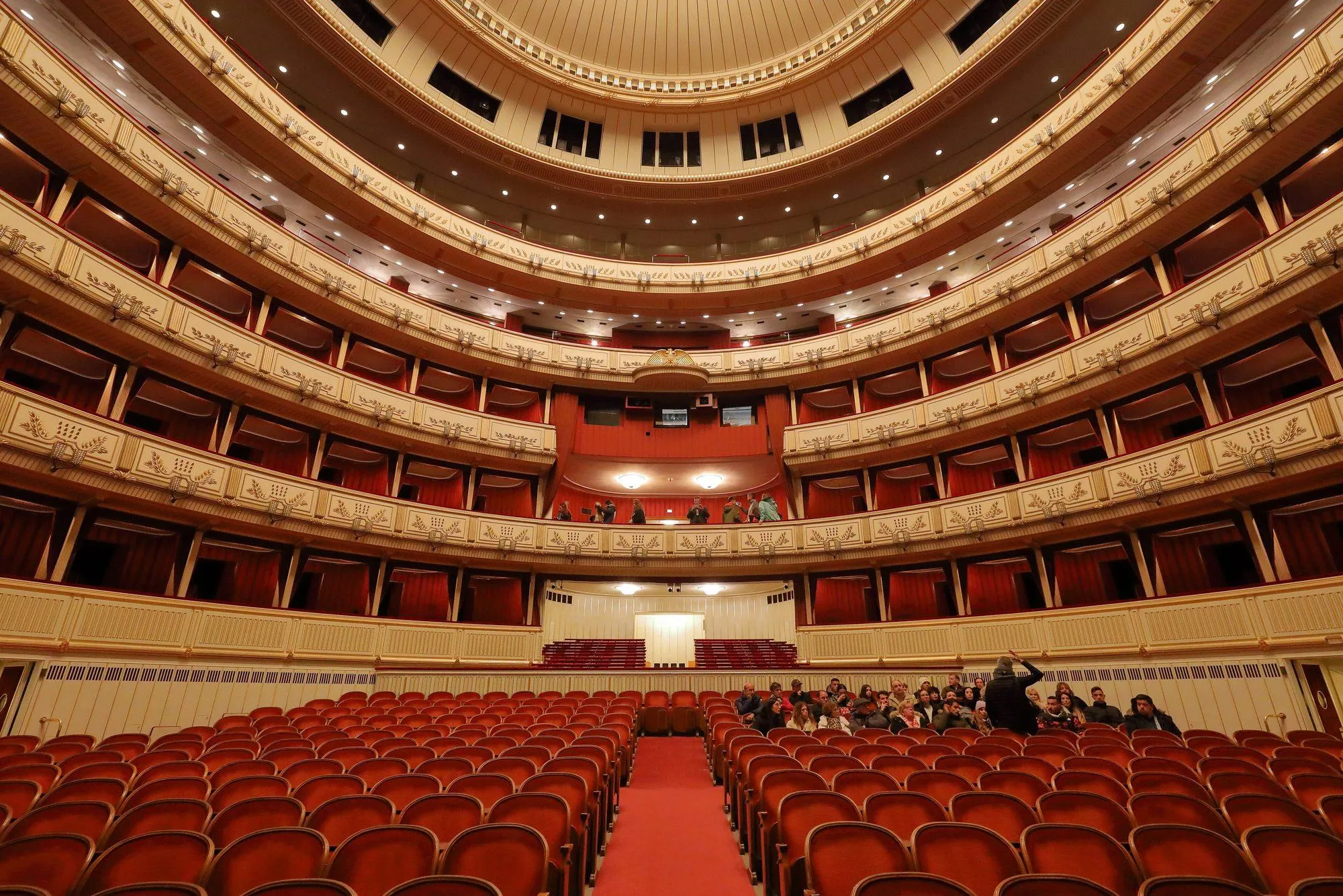 The auditorium of the Wiener Staatsoper seen from the stage: five tiers of red and gold boxes under the chandelier